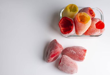 Donmuş sebzeler, beyaz bir sırt üzerinde cam bir kasede dolma biber.