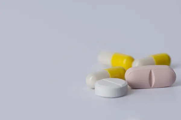 Kapsüller ve tabletler oval ve yuvarlak beyaz arkaplan üzerinde.