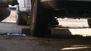 Jack lastiği değiştirmek için arabayı kaldırır.