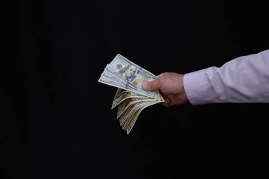 Erkek el para teklif ediyor, Amerikan doları banknotları, Amerikan doları kara arka plan, takas, ticaret ve para kazanma kavramı, finans ve iş dünyasına karşı
