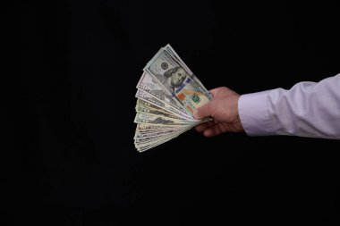 Erkek el para teklif ediyor, Amerikan doları banknotları, Amerikan doları kara arka plan, takas, ticaret ve para kazanma kavramı, finans ve iş dünyasına karşı