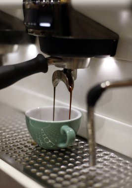 Espresso makinesi bir fincana kahve dolduruyor.