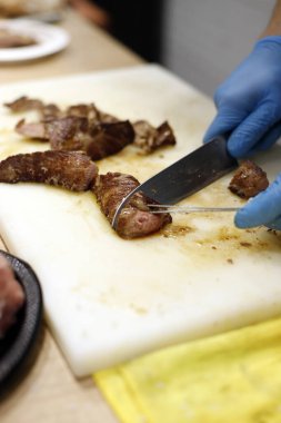 Şef mutfak tahtasındaki bıçakla sığır filetosu kesiyor.