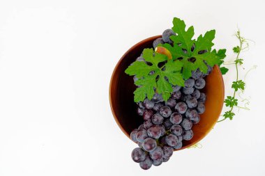 Taze meyve, mor üzüm, Kyoho üzümü, beyaz arka planda izole edilmiş tahta bir fincanda yapraklar.