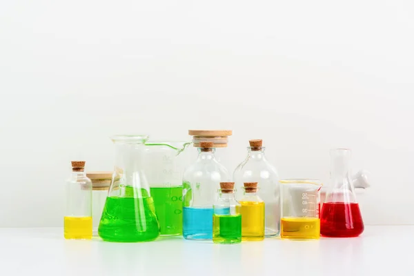 白桌科学实验室的一些试管 装有烧杯 烧瓶和充满五颜六色液体背景的试管 — 图库照片