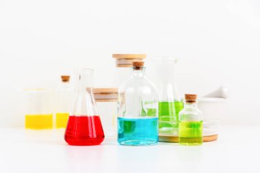 Beyaz masa bilim laboratuarında deney tüpleri, şişeler ve renkli sıvılarla dolu test tüpleri.