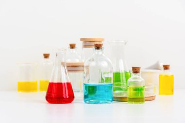 Beyaz masa bilim laboratuarında deney tüpleri, şişeler ve renkli sıvılarla dolu test tüpleri.