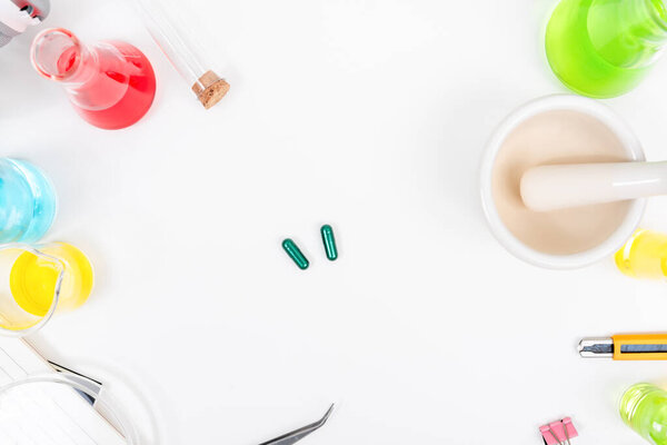 Top view table science lab chemistry flask with beakers, flasks, and test tubes filled with colorful liquids background