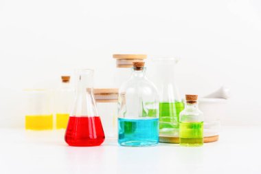 Beyaz masa bilim laboratuarında deney tüpleri, şişeler ve renkli sıvılarla dolu test tüpleri.