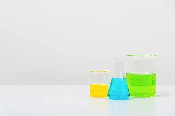 カラフルな液体で満たされたビーカー フラスコ およびテスト管が付いている白いテーブル科学の実験室のいくつかのテスト管 — ストック写真