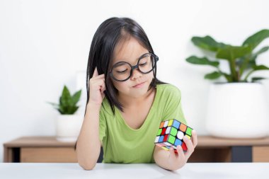 Asyalı küçük şirin kız Rubik 'in küpünü elinde tutuyor. Rubik Küpü, çocukların zekasını artıran bir oyundur..
