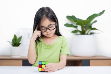 Asyalı küçük şirin kız Rubik 'in küpünü elinde tutuyor. Rubik Küpü, çocukların zekasını artıran bir oyundur..