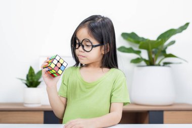 Asyalı küçük şirin kız Rubik 'in küpünü elinde tutuyor. Rubik Küpü, çocukların zekasını artıran bir oyundur..