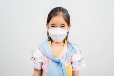 Koronavirüs salgınını korumak için maske takan Asyalı küçük kız çocuğu ve boş bir arkaplanı işaret eden yeni virüs Covid-19. 