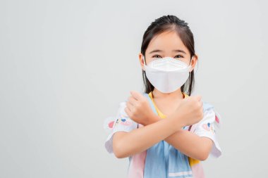 Koronavirüs salgınını korumak için maske takan Asyalı küçük kız çocuğu ve boş bir arkaplanı işaret eden yeni virüs Covid-19. 