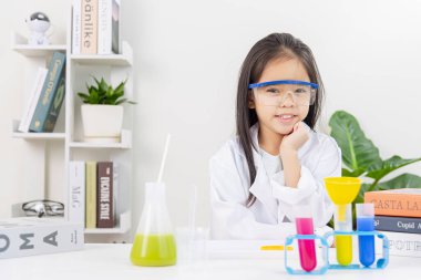 Kimya bilimi için mataraları olan mutlu bir Asya kızı beyaz bir arka planda izole edilmiş.