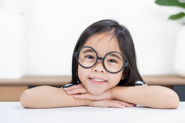 Asyalı Şirin Küçük Kız Oturuyor Gülümsüyor Gözlük Takıyor — Stok fotoğraf