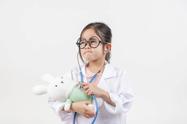 アジアの小さな女の子は 白で孤立した医者と小さなウサギの人形を演じます — ストック写真