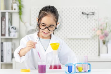 eğitim, bilim ve çocuk konsepti gözlüklü kız büyüteçle laboratuarda kimyasallarla test tüpü üzerinde çalışıyor.