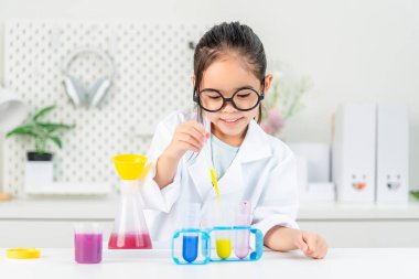 eğitim, bilim ve çocuk konsepti gözlüklü kız büyüteçle laboratuarda kimyasallarla test tüpü üzerinde çalışıyor.
