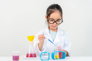 eğitim, bilim ve çocuk konsepti gözlüklü kız büyüteçle laboratuarda kimyasallarla test tüpü üzerinde çalışıyor.