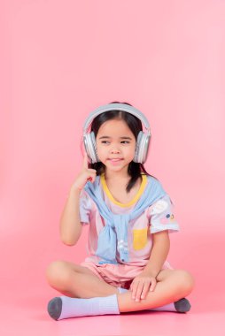 Asya 'lı küçük tatlı kız kulaklık takıyor, uzaktan öğretmenle bilgisayar kullanarak video dersi alıyor, internette çalışıyor, evde eğitim görüyor.