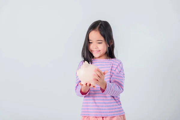 Kleines Asiatisches Mädchen Spart Geld Einem Sparschwein Lernt Etwas Über lizenzfreie Stockbilder