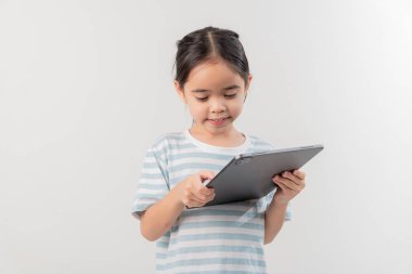 Gülümseyen küçük kız ilmekliyor ve elinde bir tablet tutuyor. 