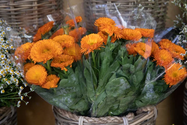 Fresh cut bright bouquets of Calendula officinalis with orange petals blossom or Pot marigold flowers at the greek garden flowers shop in spring. Horizontal. Close-up.