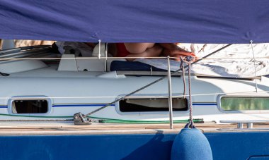 Bikini mayo giymiş genç bir kadın sıcak bir yaz günü siesta sırasında ya yelkenlinin güvertesinde uyur ya da dinlenir. Yunanistan 'ın Kastos adasında yaz tatili. Yatay.