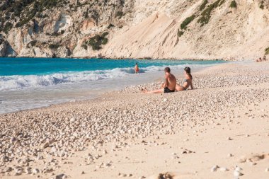 Genç aile yaz tatili sırasında Yunanistan 'ın Kefalonia adasındaki Myrtos plajında dinlenir. Yatay olarak. Seçici odak.