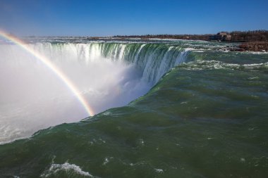 Kanada, Ontario 'da bulunan nefes kesici bir şelale olan Niagara Şelalesi' ndeki uçurumdan sular akıyor. Sisin üzerinde canlı bir gökkuşağı kemeri, bu ikonik manzaranın doğal güzelliğini arttırıyor..