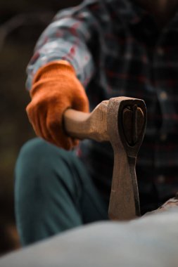 Ekose gömlekli ve turuncu eldivenli adamın tuttuğu Balta Bıçağının Yakın Çekimi.