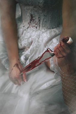 Beyaz elbiseli bir gelinin dramatik portresi. Elinde kanlı bir bıçak, sisli bir ışıkta oturuyor.