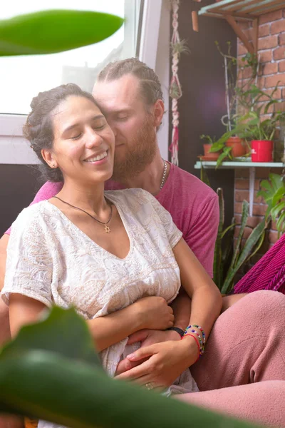 Güzel bir çift evde birlikte vakit geçiriyorlar. Mutlu, hamile, Latin bir kadın. Kanepede oturan genç bir aile.