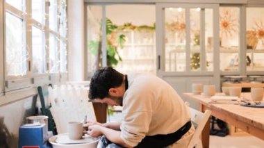 Çömlekçilik stüdyosunda el yapımı seramik kullanan genç bir adam.