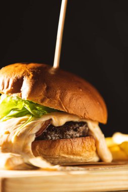 Tahta bir tahtanın üzerine şişle şişlenmiş peynirli hamburger ayrıntıları. Birinci sınıf gurme burger.