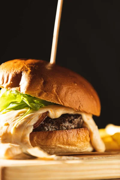 Tahta bir tahtanın üzerine şişle şişlenmiş peynirli hamburger ayrıntıları. Birinci sınıf gurme burger.