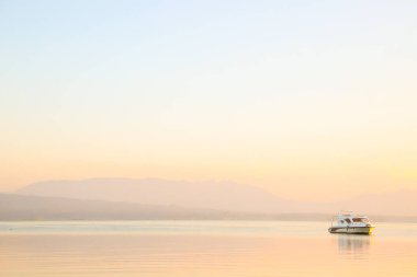 Toba Gölü 'nde güzel bir altın gün doğumu. Şafakta göl boyunca giden bir tekne. Panorama manzarası. Gün batımında suda yansıması olan gölde bir tekne.
