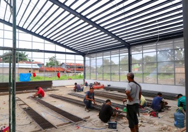 İnşaat işçilerinin inşaat alanındaki faaliyetleri, kask ve kişisel koruyucu ekipman kullanmadan çatı kurulumu için kaynak yaparken