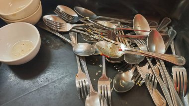 Yemeklerin kirli kaşıkları ve çatalları ve kirli masa düzenlerinin arka planı. Yemekten sonra temiz, boş bir tabağın tepesinden görünüm.