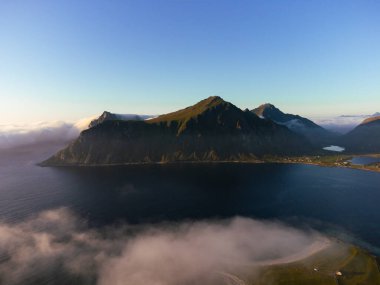 Lofoten 'da güzel bir manzaranın hava görüntüsü sisli bir günde bir dağ, yukarıdaki mavi gökyüzü