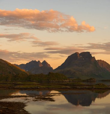 Dağların yansıması olan dağ gölü, Lofoten, Norveç. Gece yarısı güneş ışığı.
