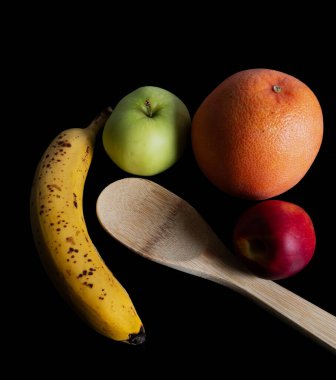 Taze meyve ve siyah arka planda izole edilmiş bir tahta kaşık..