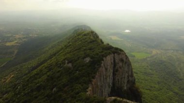 Fransa 'nın Montpellier yakınlarındaki kayalık bir tepe olan Pic Saint Loup' un hava manzarası. Muhteşem uçurumlar ve sisli bir yaz günü. 4K çözünürlük ve 30fps.