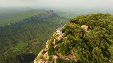 Fransa 'nın Montpellier yakınlarındaki kayalık bir tepe olan Pic Saint Loup' un hava manzarası. Muhteşem uçurumlar ve sisli bir yaz günü. 4K çözünürlük ve 30fps.