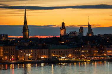 İsveç 'in eski Stockholm kentinin panoramik manzarası, diğerleri arasında Alman Kilisesi ve Aziz Nicholas Kilisesi' nin sarmalı, alacakaranlıkta, çarpıcı turuncu bir gökyüzü ile açıkça görülüyor..