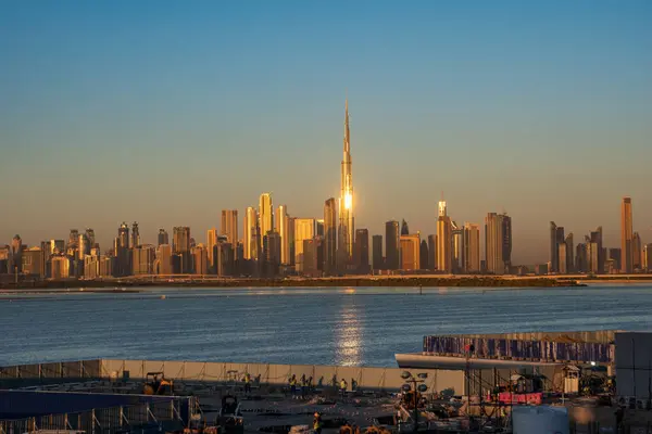 Burj Halife ve Dubai finans bölgesi gündoğumunda ufuk çizgisi, ön planda devam eden yeni bir yüksek bina inşaatı ile