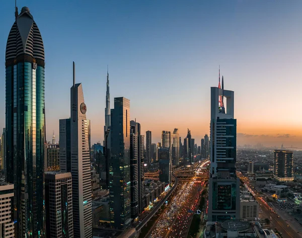 Sheikh Zayed yolunun yoğun saatinde Dubai 'nin yüksek görüş açısı. Alacakaranlıkta Burç Halife ve ön planda modern gökdelenlerle birlikte.