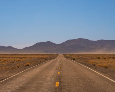 ABD 'nin güneybatısında, 51. bölgeye yakın Nevada' da ıssız bir yol (eyalet karayolu 375), kurak çöl manzarası ve parlak ışık.